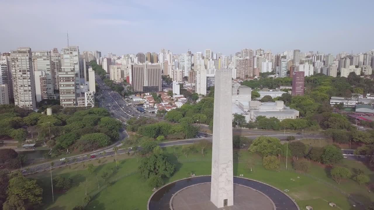 Monumento dell'Obelisco nel Parco Ibirapuera, nel centro di San Paolo, Brasile - ripresa aerea in salita dello skyline con edifici