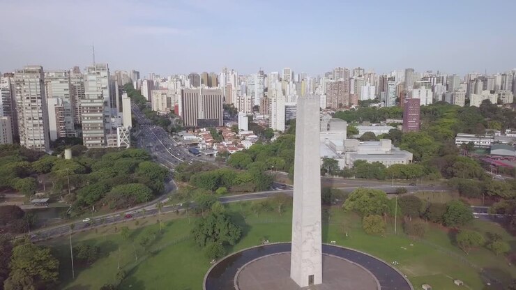 Monumento dell'Obelisco nel Parco Ibirapuera, nel centro di San Paolo, Brasile - ripresa aerea in salita dello skyline con edifici