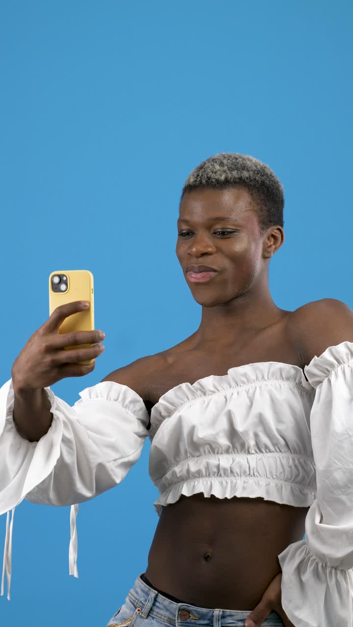 Persona sicura di sé che si scatta selfie con lo smartphone su sfondo blu