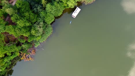 Von-Oben-Nach-Unten-Aufnahme-Mehrerer-Boote,-Die-Auf-Einem-See-Neben-Einem-Sehr-Farbenfrohen-Wald-Schwimmen,-Durch-Den-Eine-Kleine-Straße-In-Brandenburg,-Deutschland,-Führt