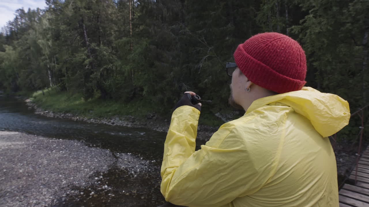 hombre fumando en un puente forestal con vistas a un río