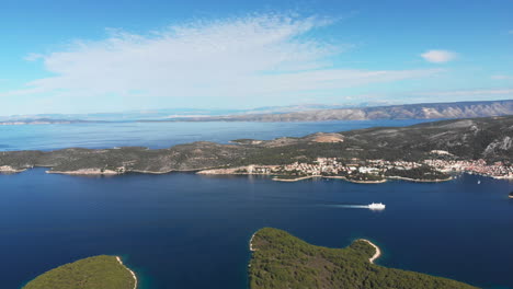 drone pushing in to the beautiful coast of the island of hvar while a ferry is passing through.