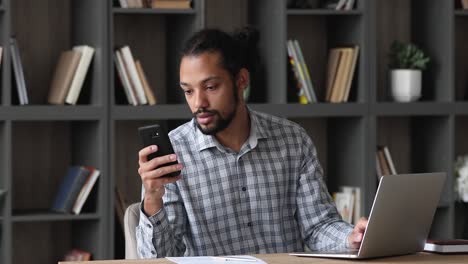 african businessman sit at desk answer the call use speakerphone