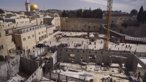 western wall reveal introduction shot from the overlook nearby. jerusalem, israel. tourists and religious individuals come to pray.