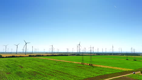 footage above the green farmlands on sunny day. modern wind farms produce green energy in the fields
