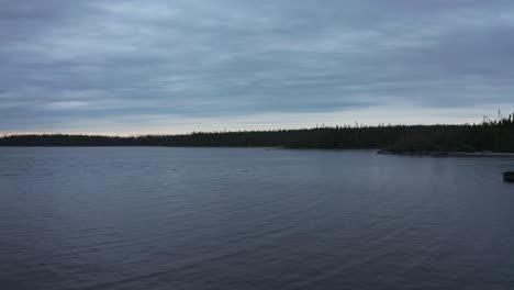 Drone-flying-over-some-fishing-boat-and-lake-over-a-cloudy-sundown