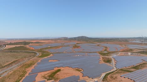 panoramic aerial overview above solar panels and farm fields with wind turbines