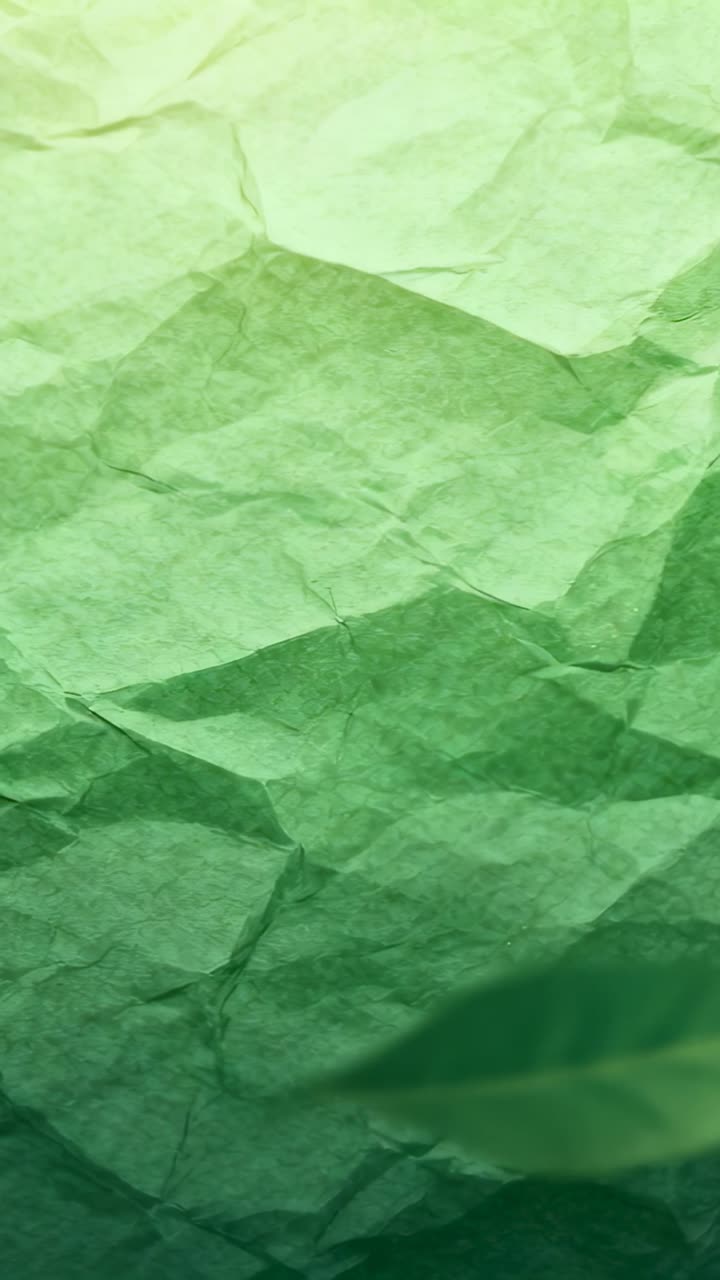 Vertical video: Displaying crumpled green sheet in close-up, briefly showing dark curved shadow
