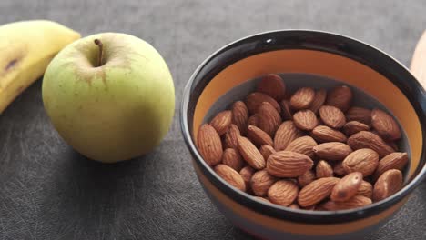 almonds in a bowl with apple and a glass of beverage