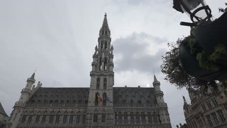 tall spire of brussels town hall rising above grand place, framed by cloudy skies, belgium