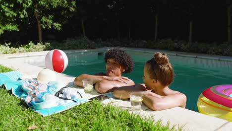relaxing by pool, diverse couple enjoying drinks and conversation on sunny day