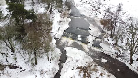 Luftdrohnenaufnahme-Eines-Kleinen-Baches-Im-Winter-Mit-Schnee-Rundherum