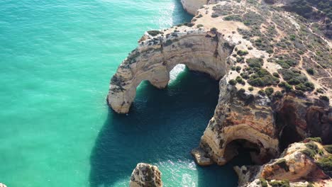 formaciones de arco de roca erosionadas por el océano en la playa de marinha al sur de portugal, tiro de aproximación aérea