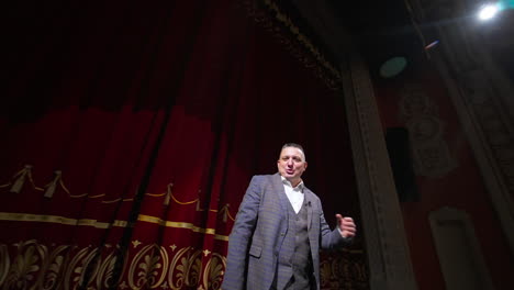 comedian rehearsing on scene. happy male actor performing in the theater dancing and singing on stage. orbital shot.