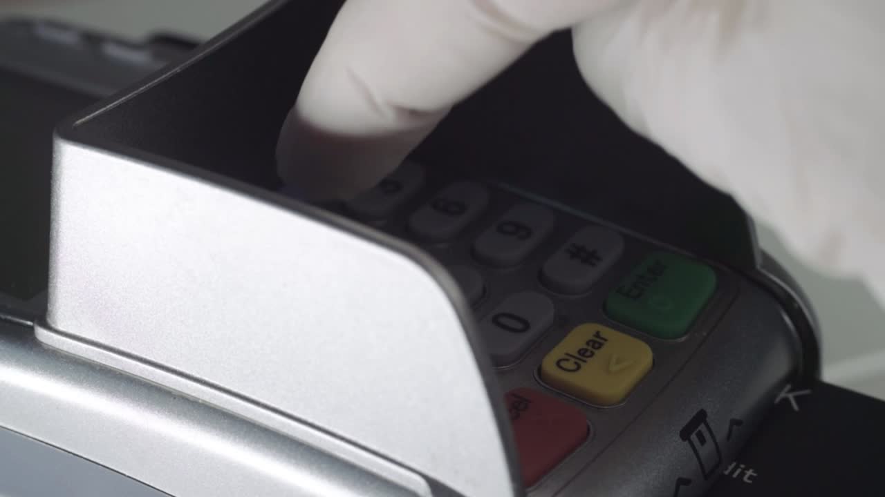Hand wearing hygienic gloves using pdq payment machine close up macro shot