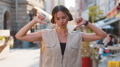 upset young woman girl showing thumbs down sign, disapproval, dissatisfied bad work, mistake in city