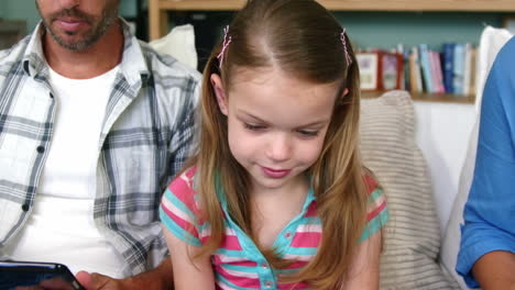 Portrait-of-a-little-girl-sitting-on-a-sofa-with-her-parents