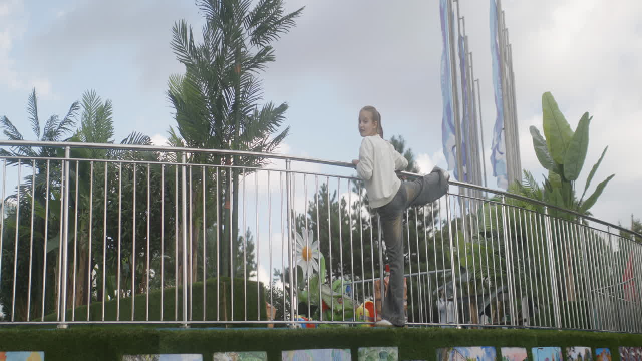 chica apoyándose en una barandilla de metal en un parque