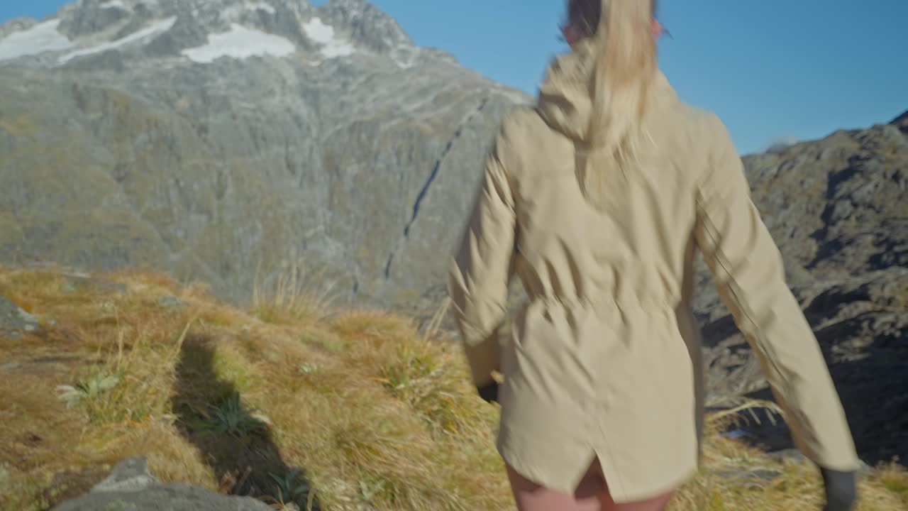 Following blond womans legs towards viewpoint in rocky alpine landscape
