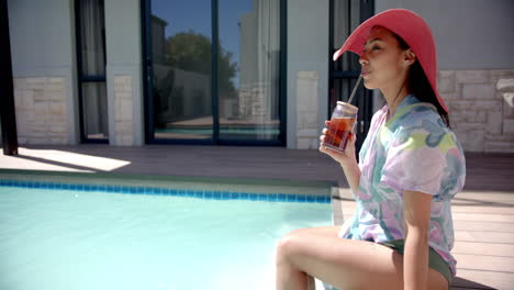 sitting by pool, woman in sunhat enjoying iced drink on sunny day, copy space