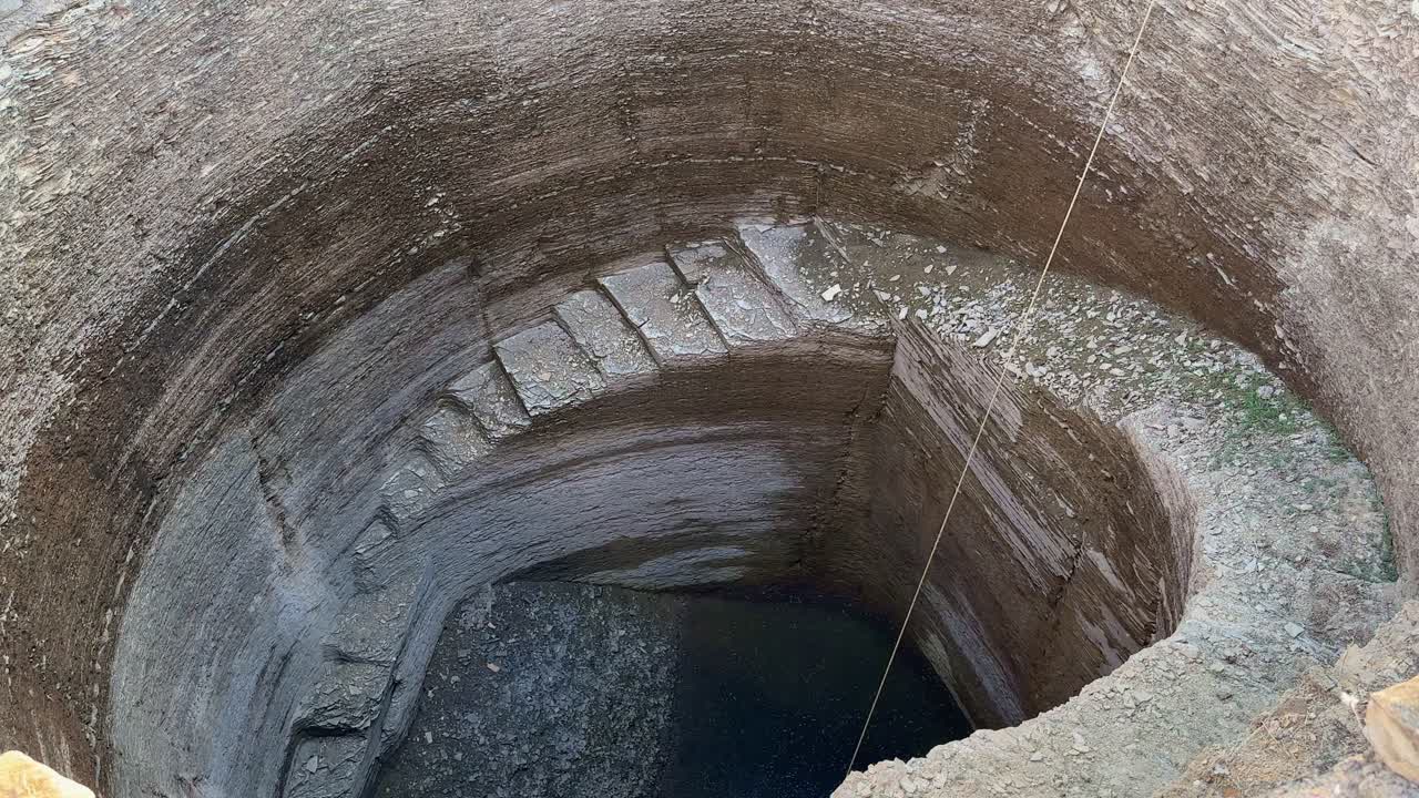 A well with steps in the middle of field with very low water left for farming in india, water shortage in india, Well irrigation is the most popular irrigation system in India