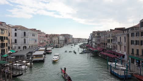 gondolas and boats travel through grand canal in historic venice, italy during overcast day