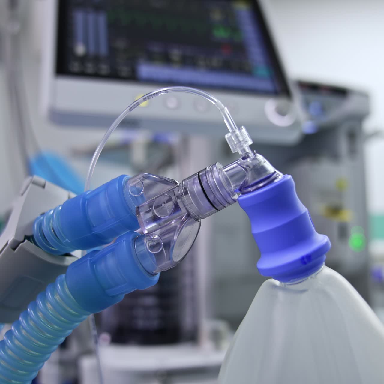 Thick tubes connected to inflating ambu bag. Close up. Lung ventilator machine working at blurred backdrop