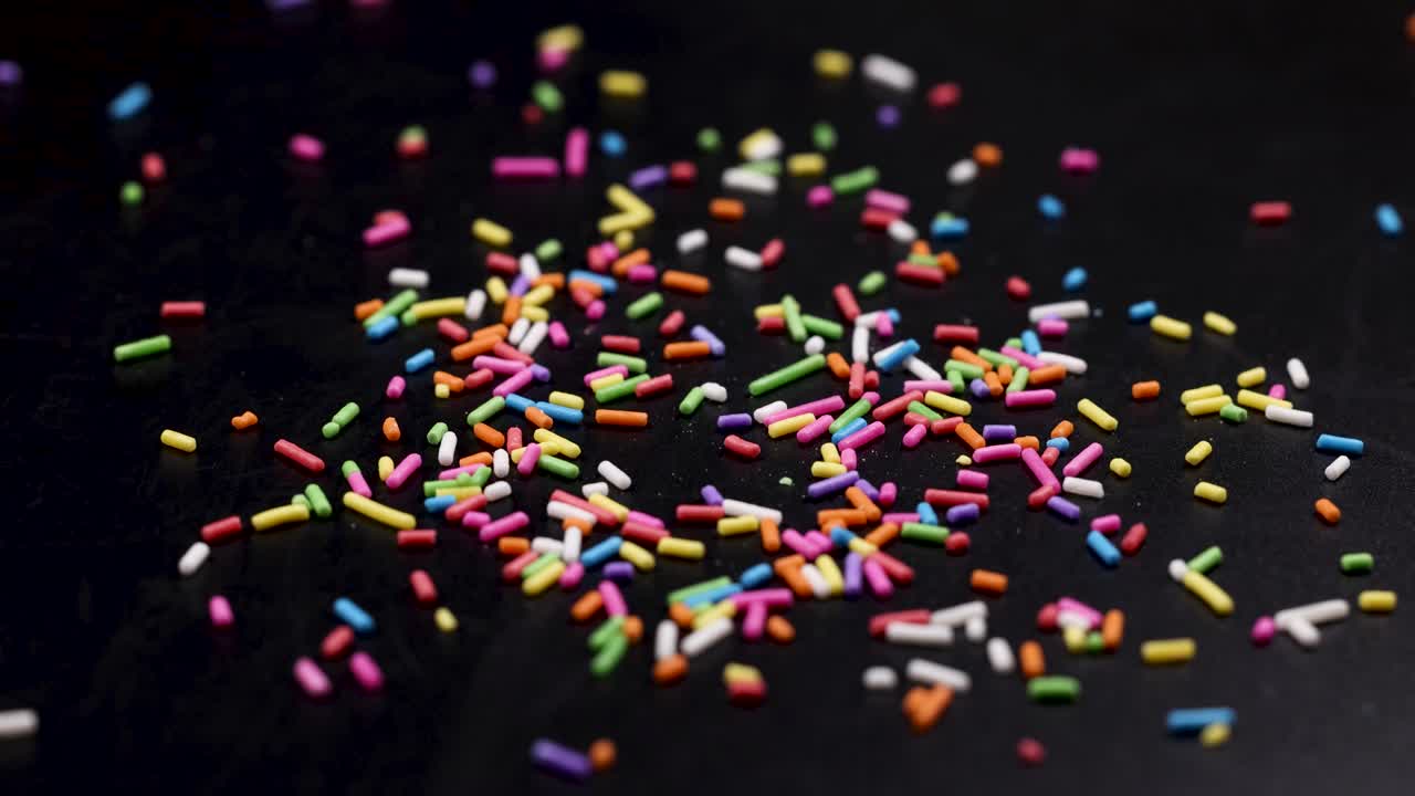 Vibrant sprinkles cascade onto a dark background