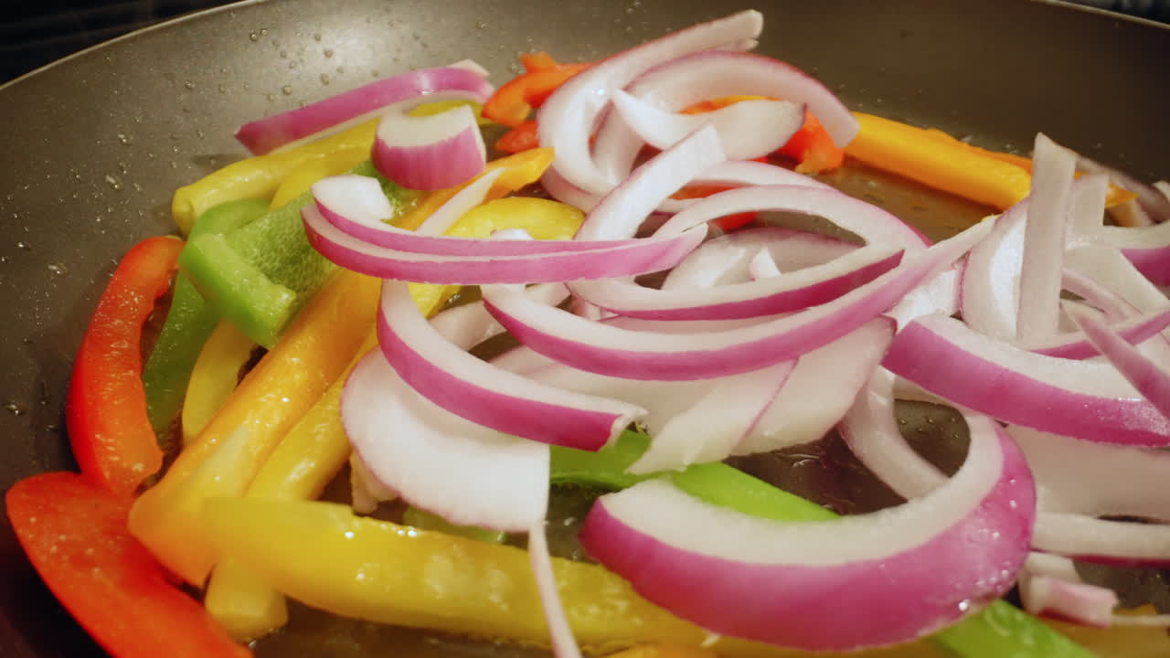 Frying fresh bell peppers and onions in a non-stick pan - macro isolated