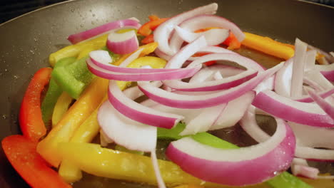 frying fresh bell peppers and onions in a non-stick pan - macro isolated