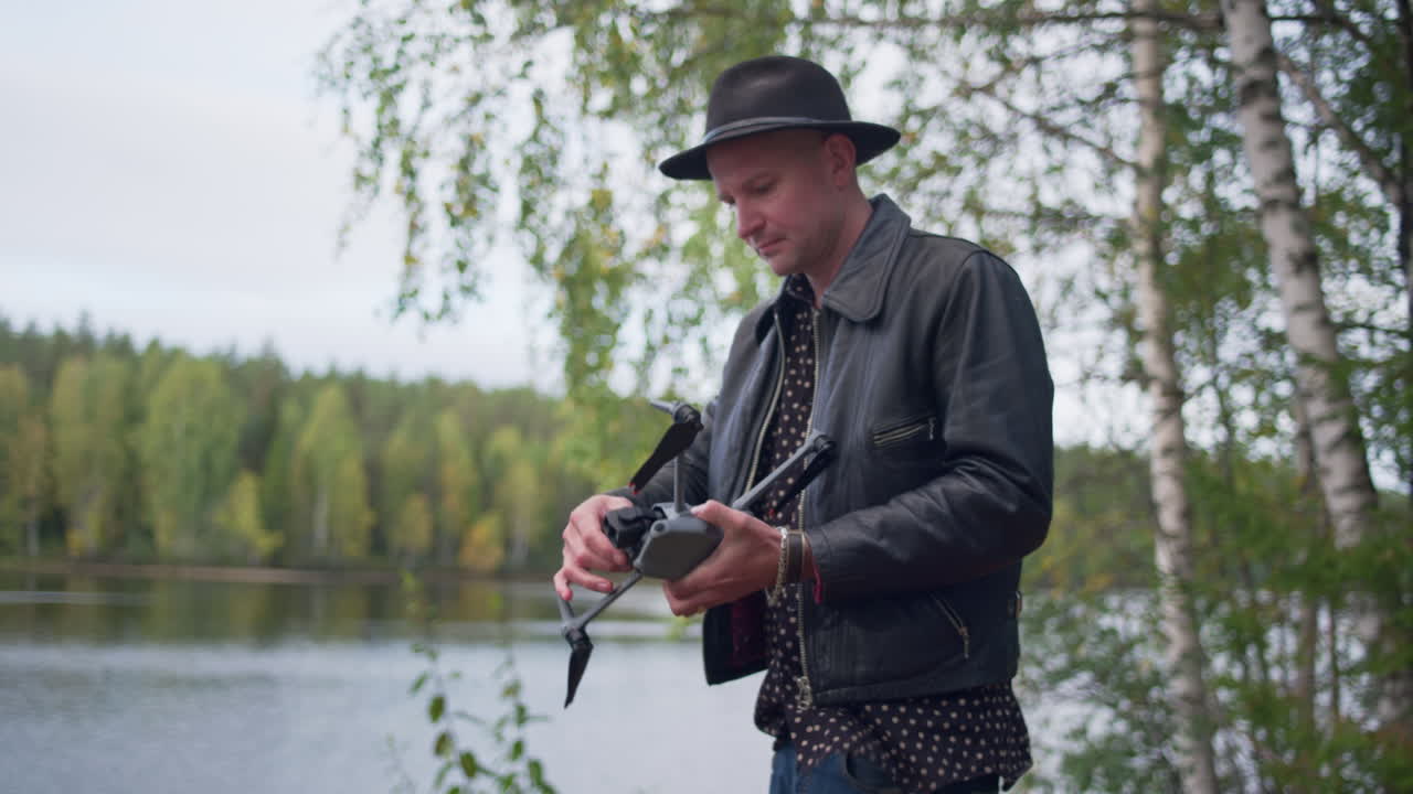 Kaukasisk mand folder propellerne ud på en DJI-drone i naturen.