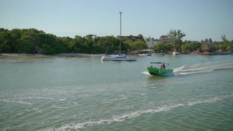 AERIAL---Speedboat-speeds-across-the-water,-Holbox,-Yucatan,-Mexico,-circling