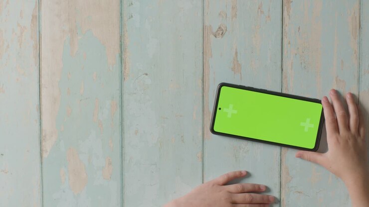 Ripresa dall'alto di un bambino che tiene in orizzontale un tablet digitale con schermo verde, guardando o riproducendo contenuti in streaming 2