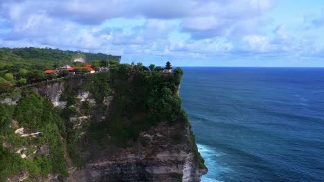 Aerial-wide-angle-view-of-Uluwatu-temple-on-tall-cliff-and-ocean-in-the-background,-Bali---Indonesia