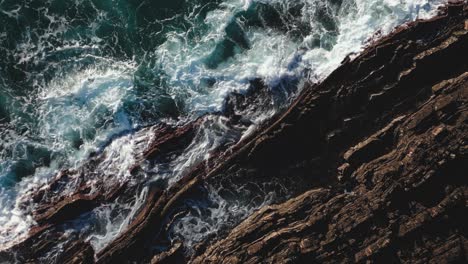 ocean reefs of portugal coast, rocky cliffs and crashing waves, drone top down view