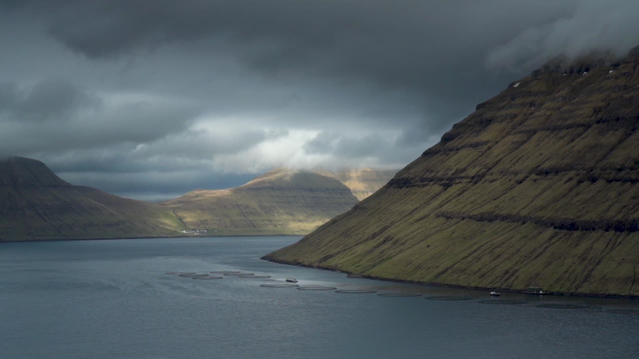 isla de kunoy bajo un cielo oscuro nublado en las islas feroe, dinamarca