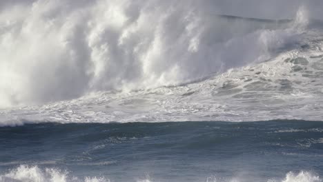 a surfer rides a big wave that breaks and washes over him