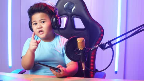 asian little boy holding mobile phone and talking to camera while live stream