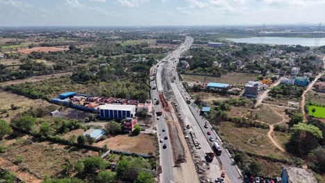 aerial view of a significant multi-lane highway construction project underway, running parallel to an existing, active road. stages of development earthworks, machinery, and construction materials