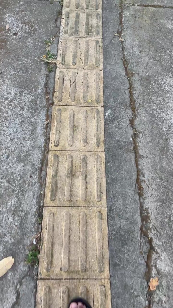 Person Walking on Tactile Paving for Visually Impaired on Sidewalk