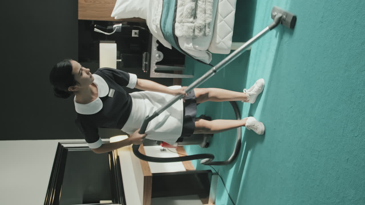 Female Housekeeper Vacuuming Floor in Hotel Room