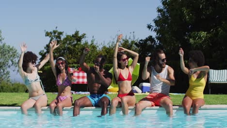 group of diverse friends dancing and enjoying while sitting by the pool