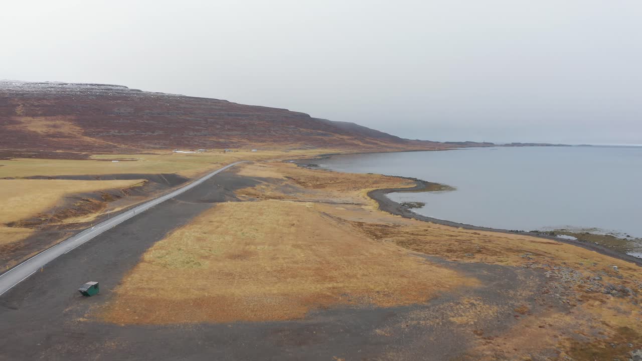 Flying Parallel to an Empty Coastal Road Surrounded by Golden Brown Hills and wild Fields in Westfjords, Iceland