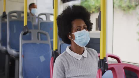 mujer de negocios afroamericana con máscara facial sentada en el autobús