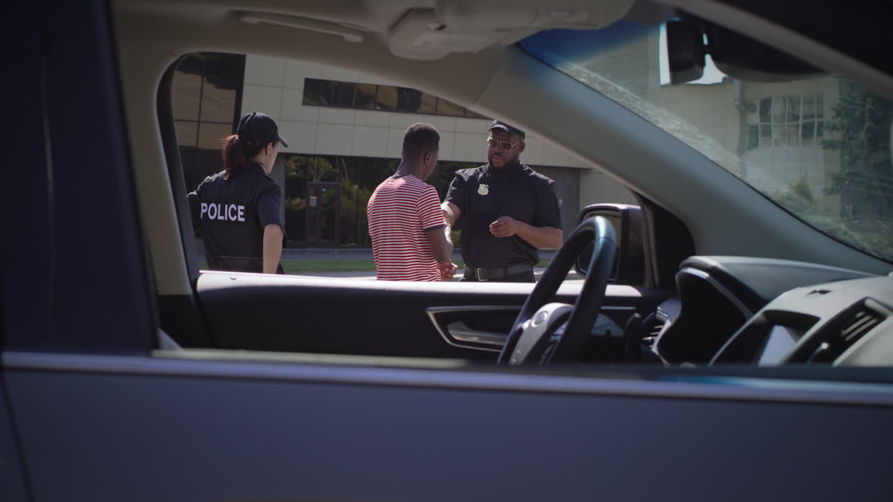 diverse Police Officers Checking Documents of Black Driver Zoom out View of African American Man Giving Driver License to Multiracial Police Officers then Returning to Car on City Street