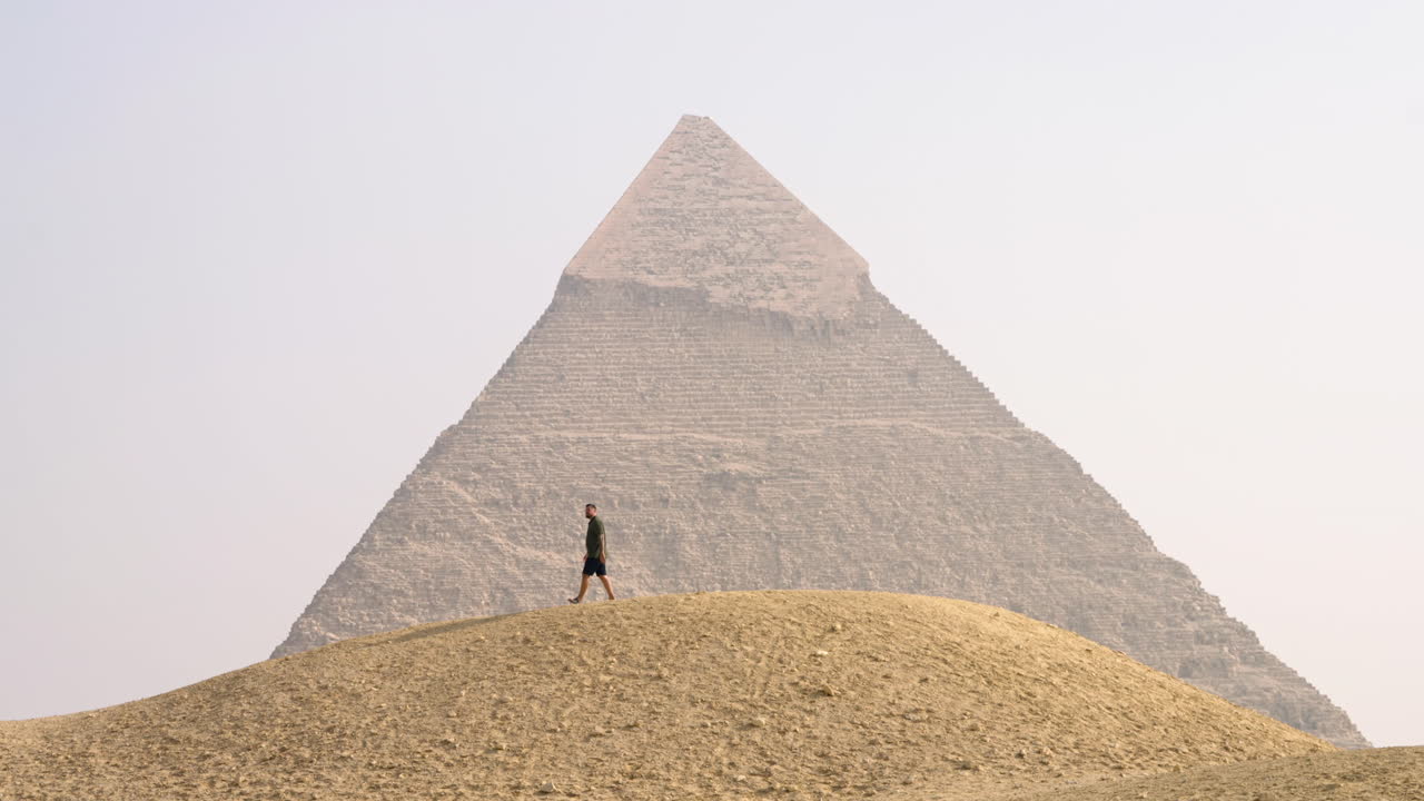 Man On The Sand Dune Hill In Front Of The Giza Plateau Pyramid Near Cairo, Egypt. Static Shot