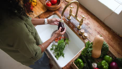 washing fresh vegetables in kitchen sink, preparing healthy meal at home