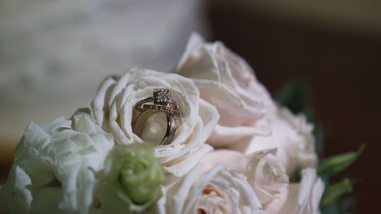 Bouquet of white roses with shiny wedding rings between their petals