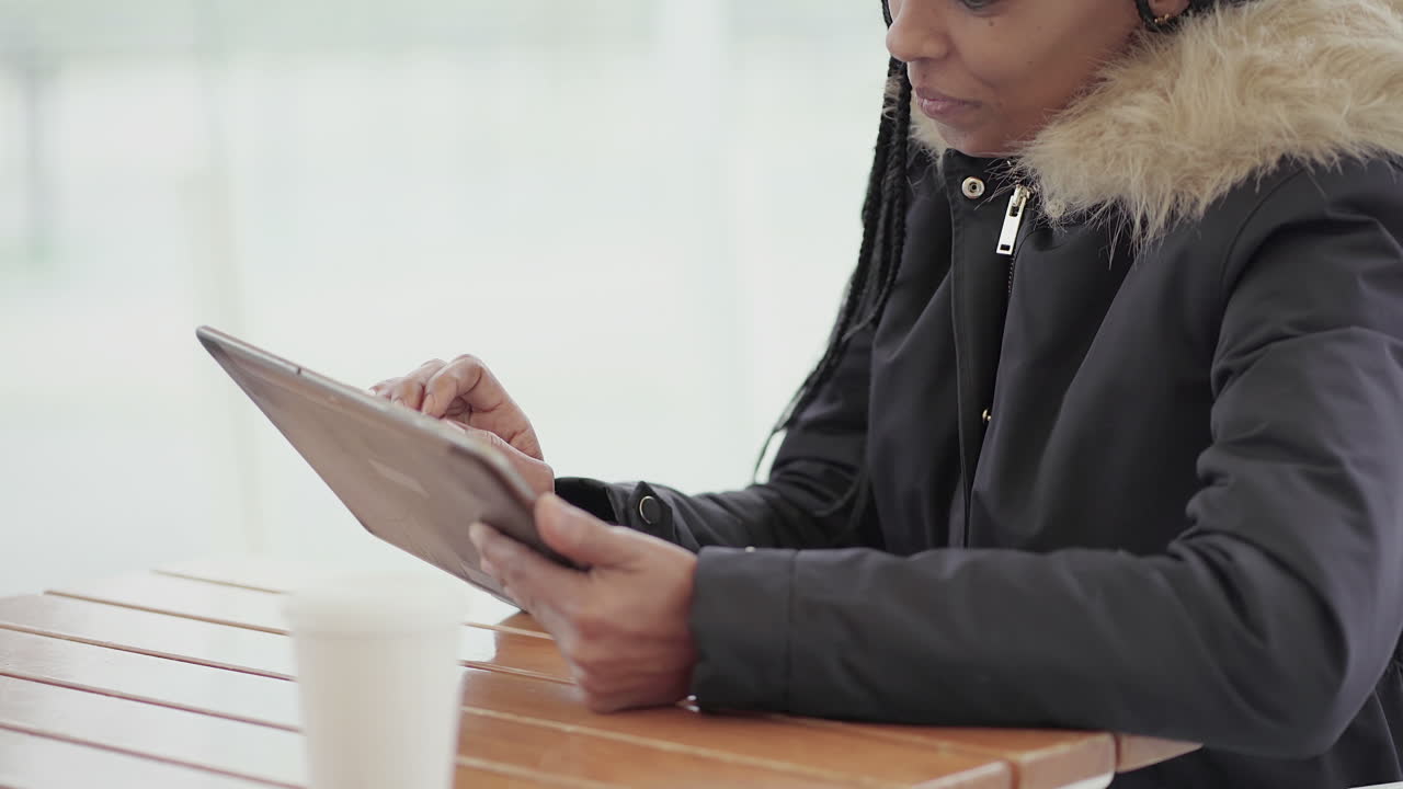 Afro-American young girl with braids in grey jacket with fur hood sitting outside