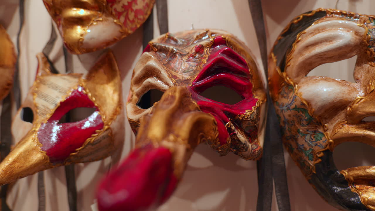 Un primo piano di maschere veneziane dal design intricato con dettagli in oro, rosso e nero, in mostra in un negozio di maschere